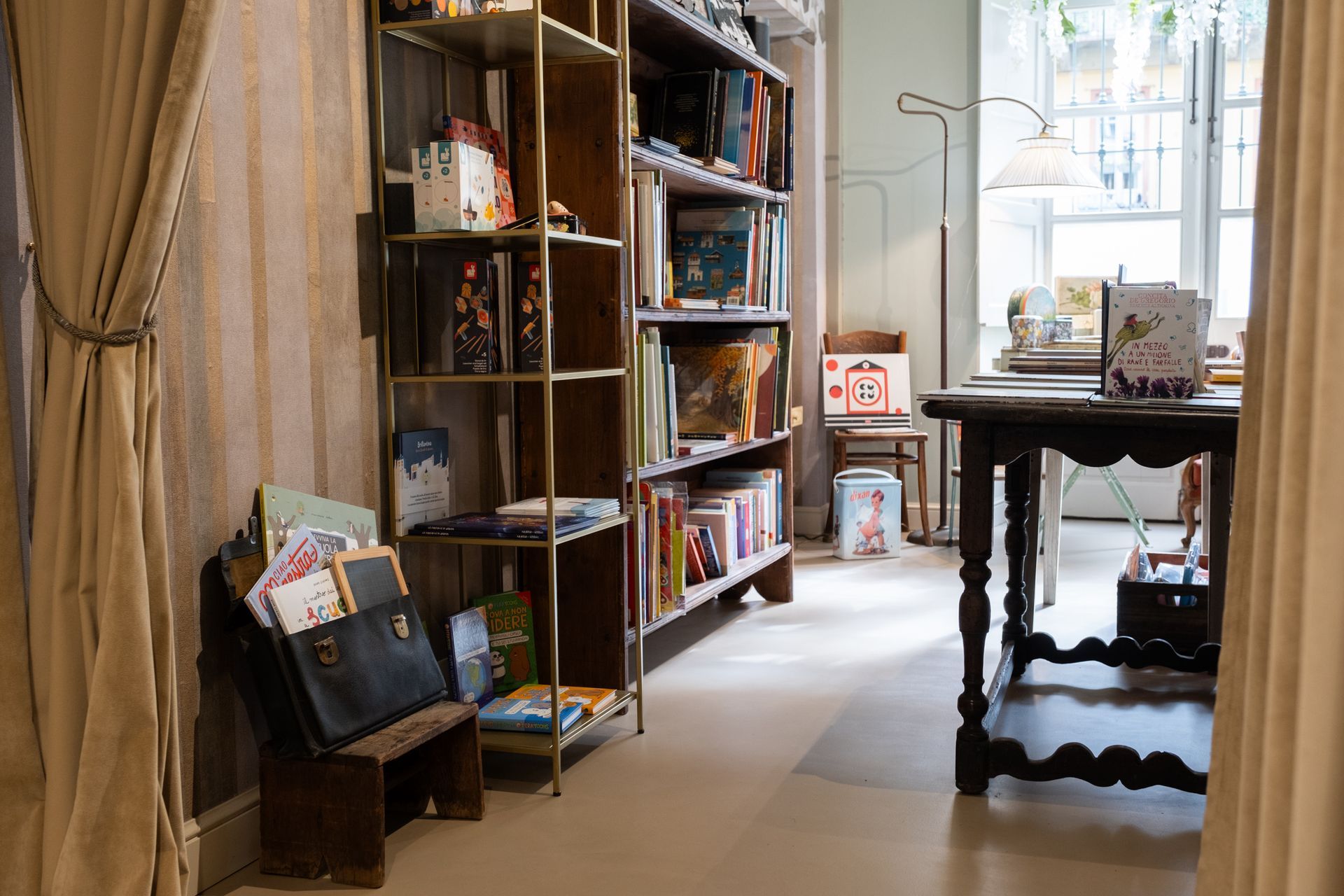 Accogliente interno di una libreria con alti scaffali in legno, tavoli espositivi e luminose vetrine.