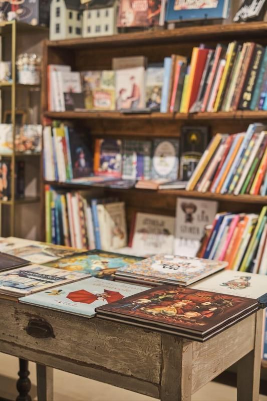 Un tavolo espositivo di libreria con libri colorati davanti a scaffali di legno pieni di libri.