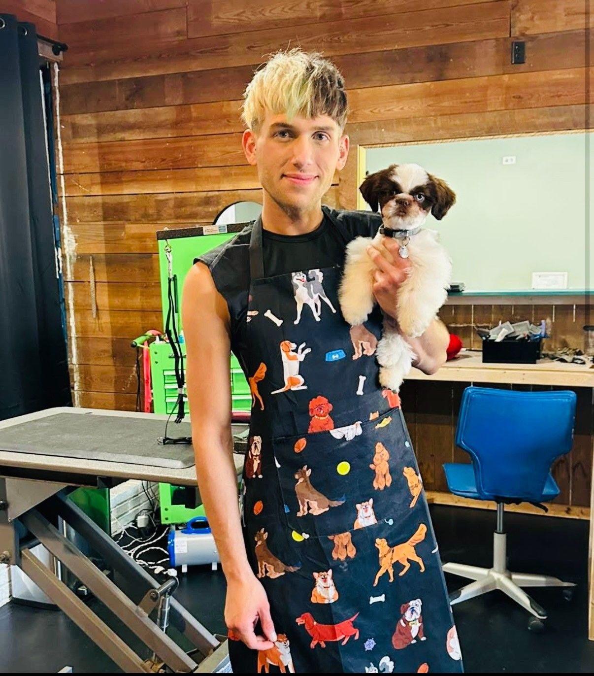 A man in an apron is holding a small dog