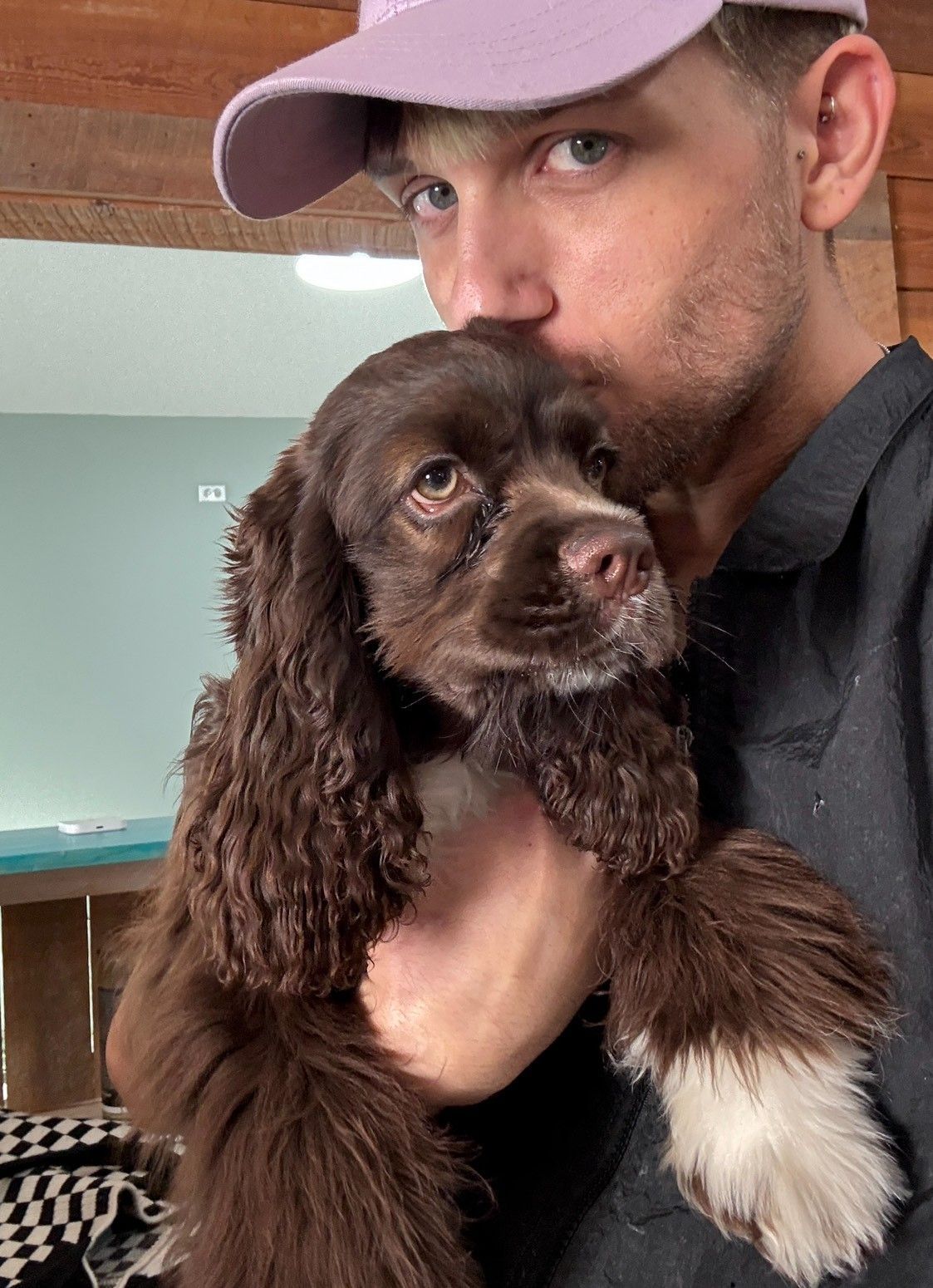 A man is holding a brown and white dog in his arms.