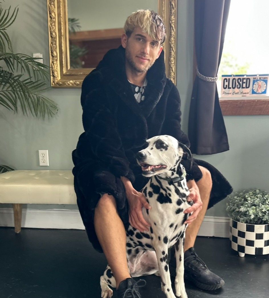 A man is sitting on a bench with a dalmatian dog