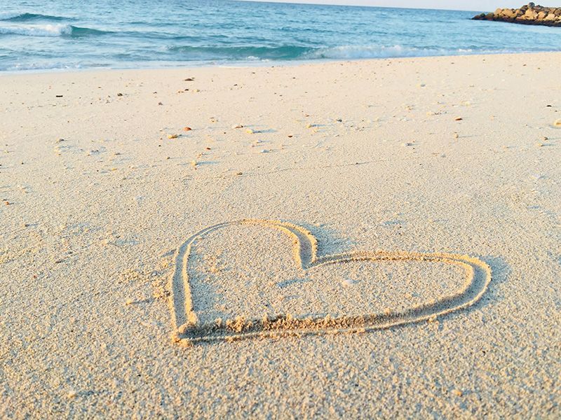 A heart is drawn in the sand on a beach