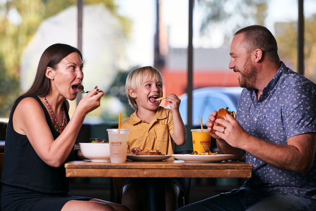 A family is sitting at a table eating food.