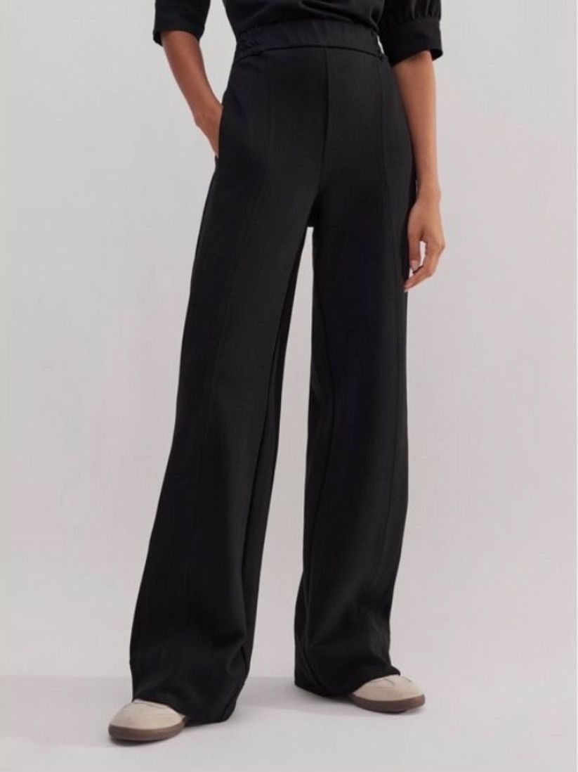 A woman is wearing a pair of black wide leg pants