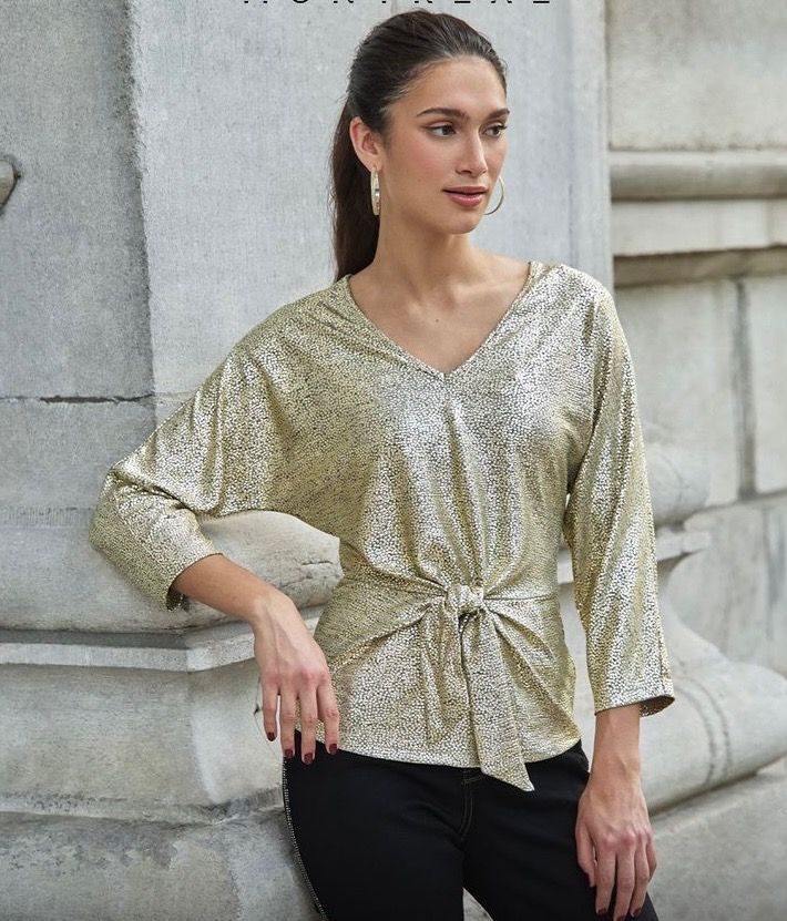 A woman is wearing a sequined top and black pants.