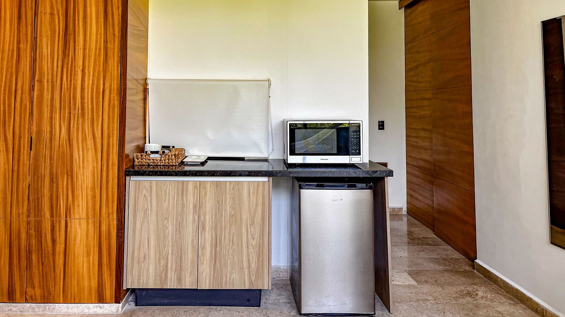 Una pequeña cocina con microondas, mininevera y armarios de madera.