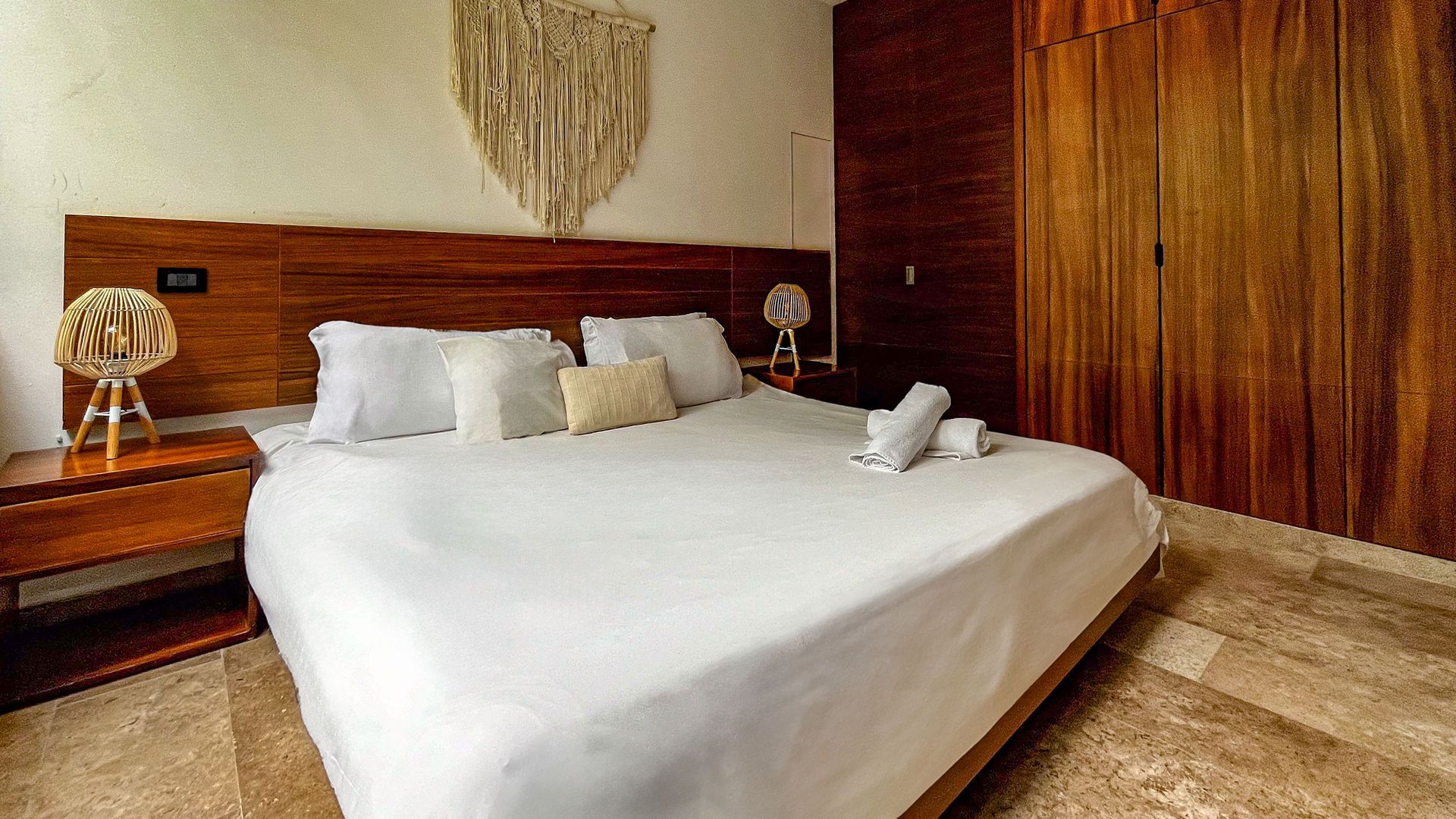 Dormitorio con cama grande, cabecero de madera, mesitas de noche y armario empotrado.