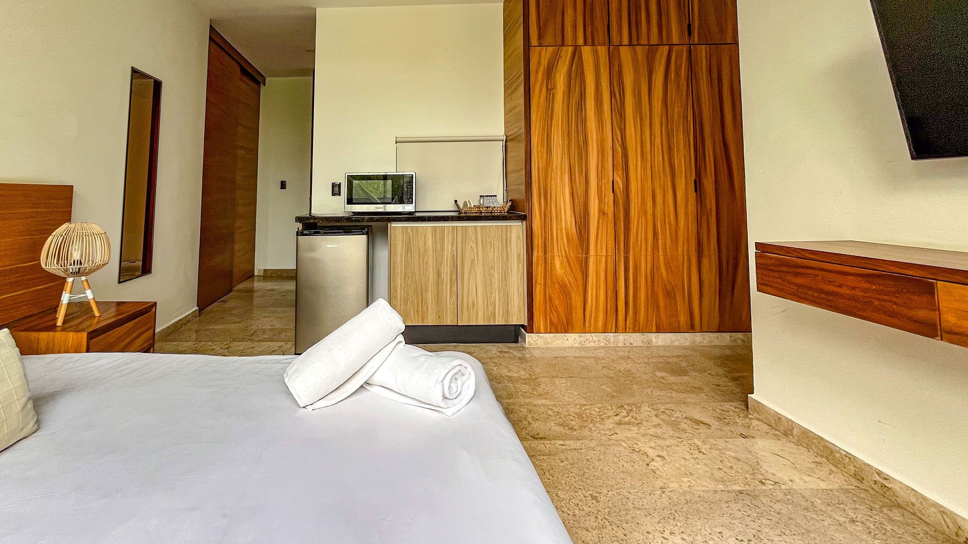 Un apartamento tipo estudio con cama, cocina americana y armarios de madera para guardar cosas.