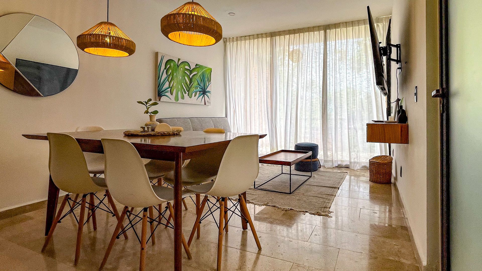 Comedor con mesa, sillas, arte, lámparas, sofá y TV.