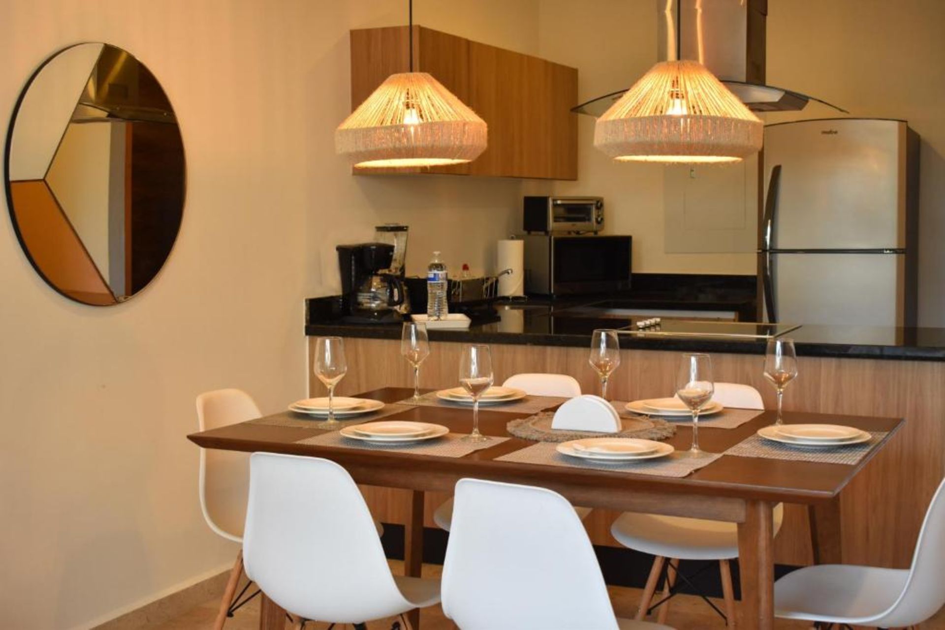 Comedor con mesa de madera para seis personas, espejo y cocina.