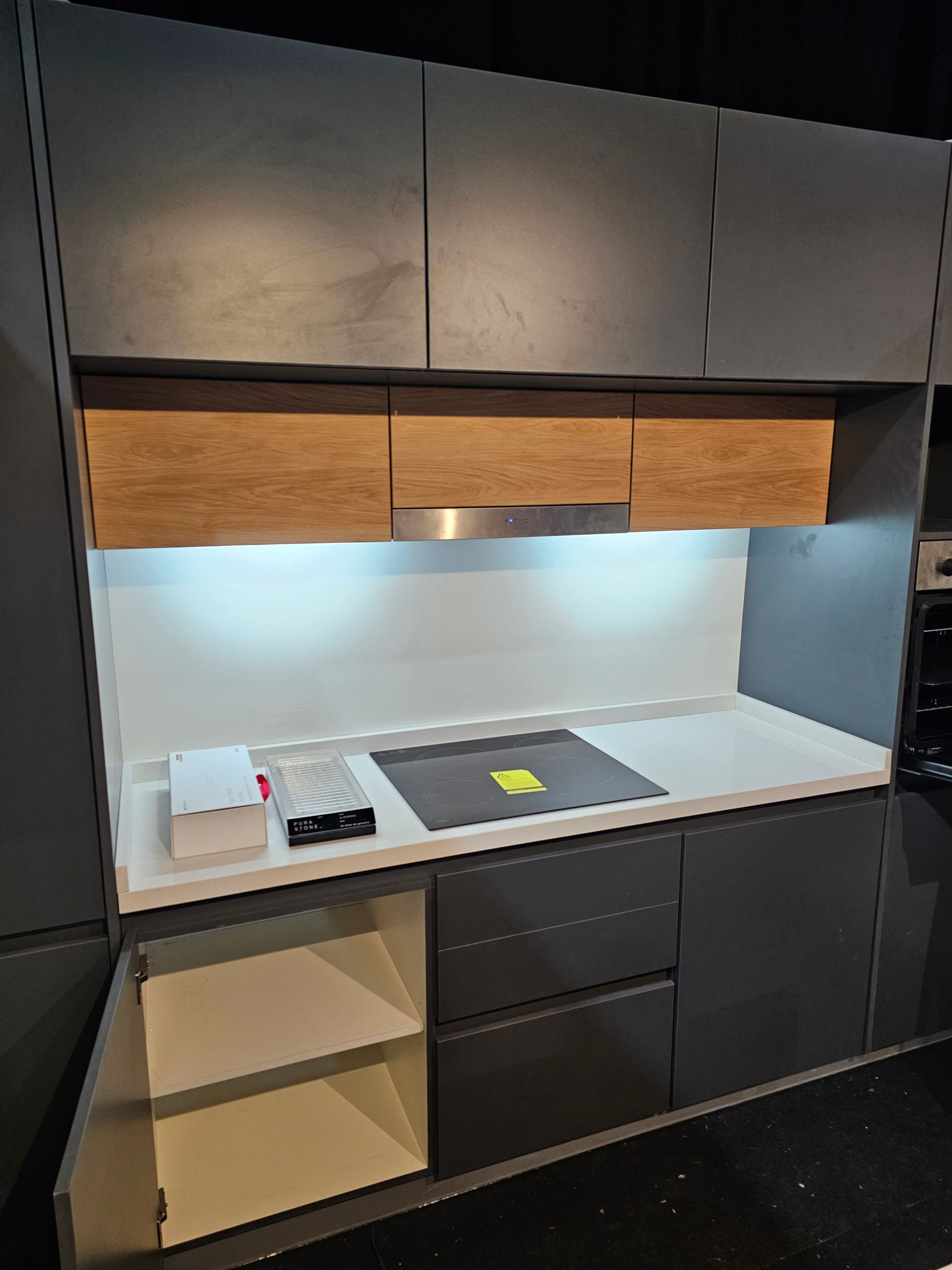 Configuración de muebles de cocina modernos con tonos grises y madera, que incluye una estufa y un gabinete abierto.