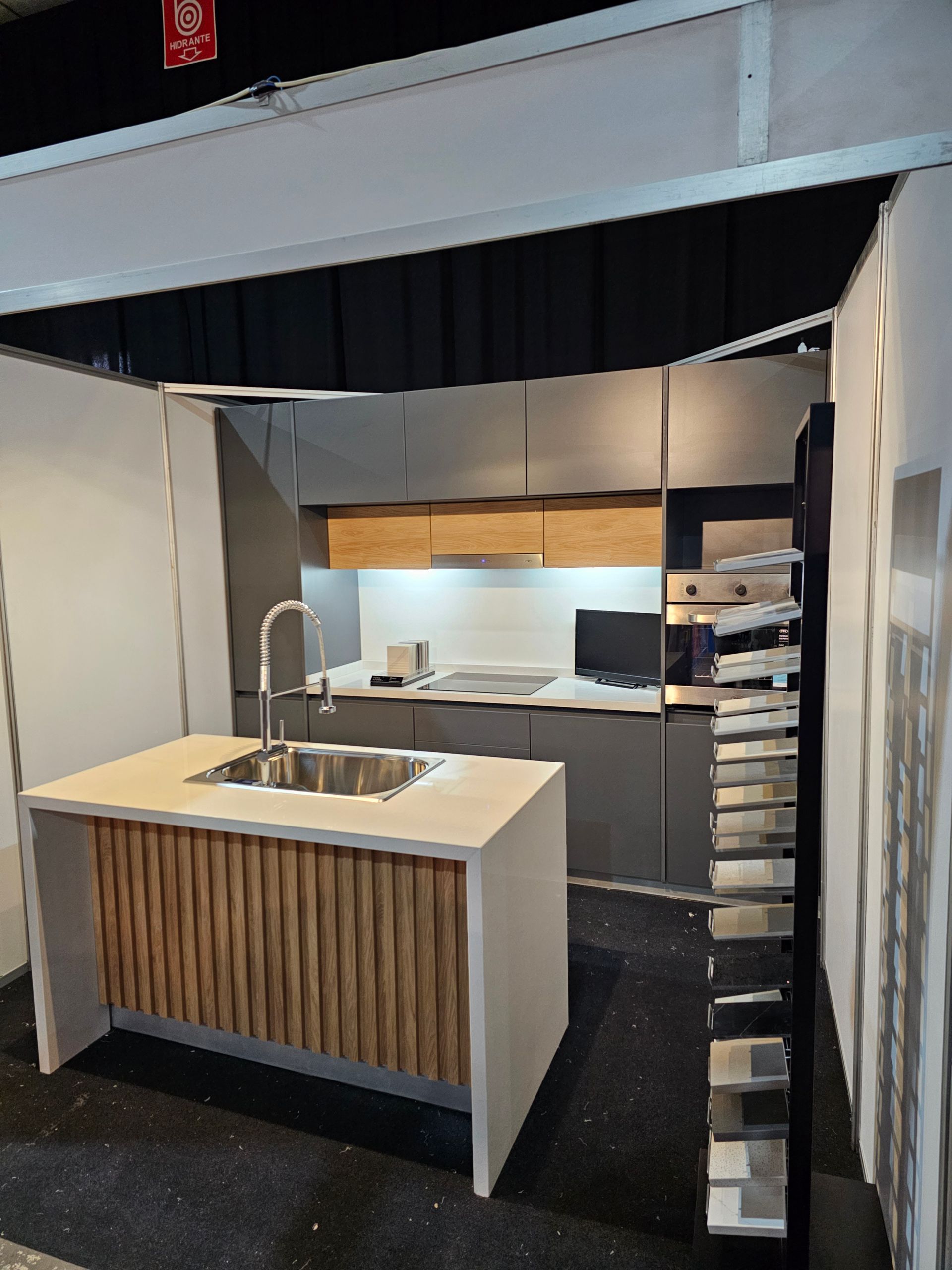 Exhibición de cocina moderna con isla y gabinetes oscuros; acento de madera.