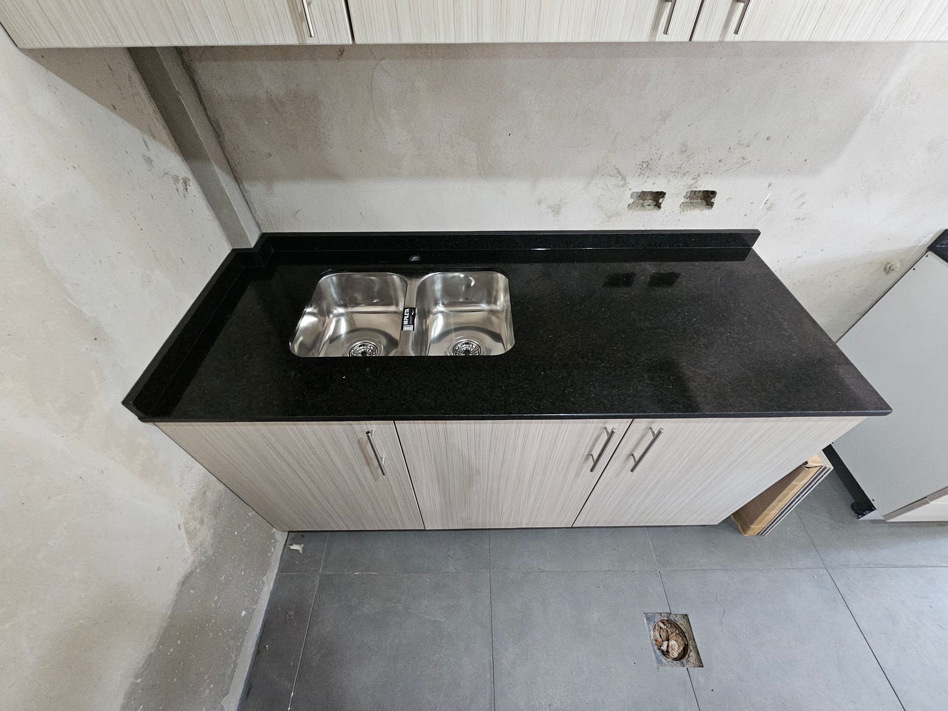 Mueble de cocina con encimera color negro y fregadero doble en acero inoxidable.