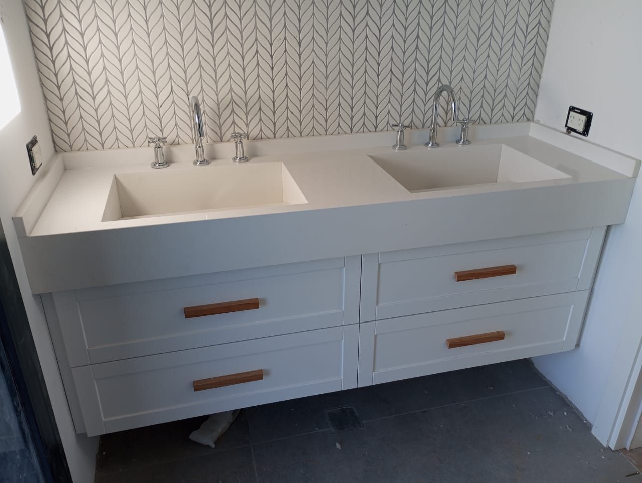 Tocador de dos lavabos de color blanco con cajones, tiradores marrones y salpicadero de azulejos estampados.