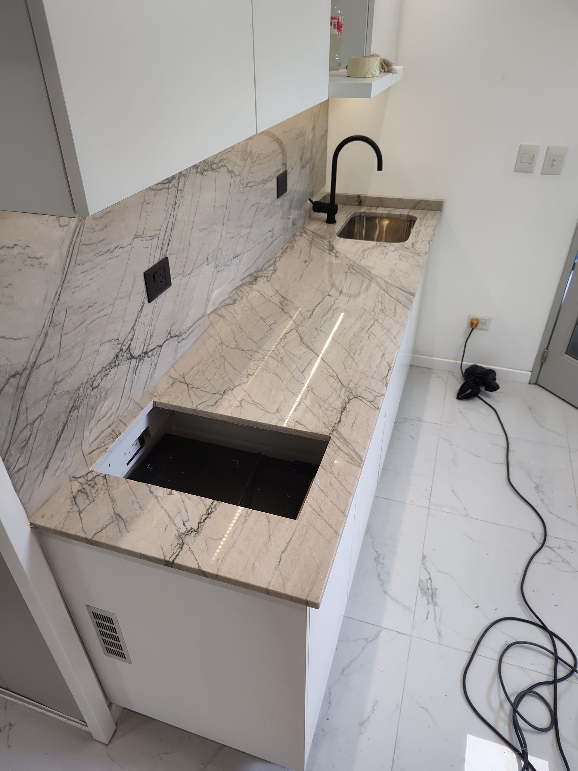 Encimera de cocina blanca con grifo y fregadero negros, instalada con protector contra salpicaduras.