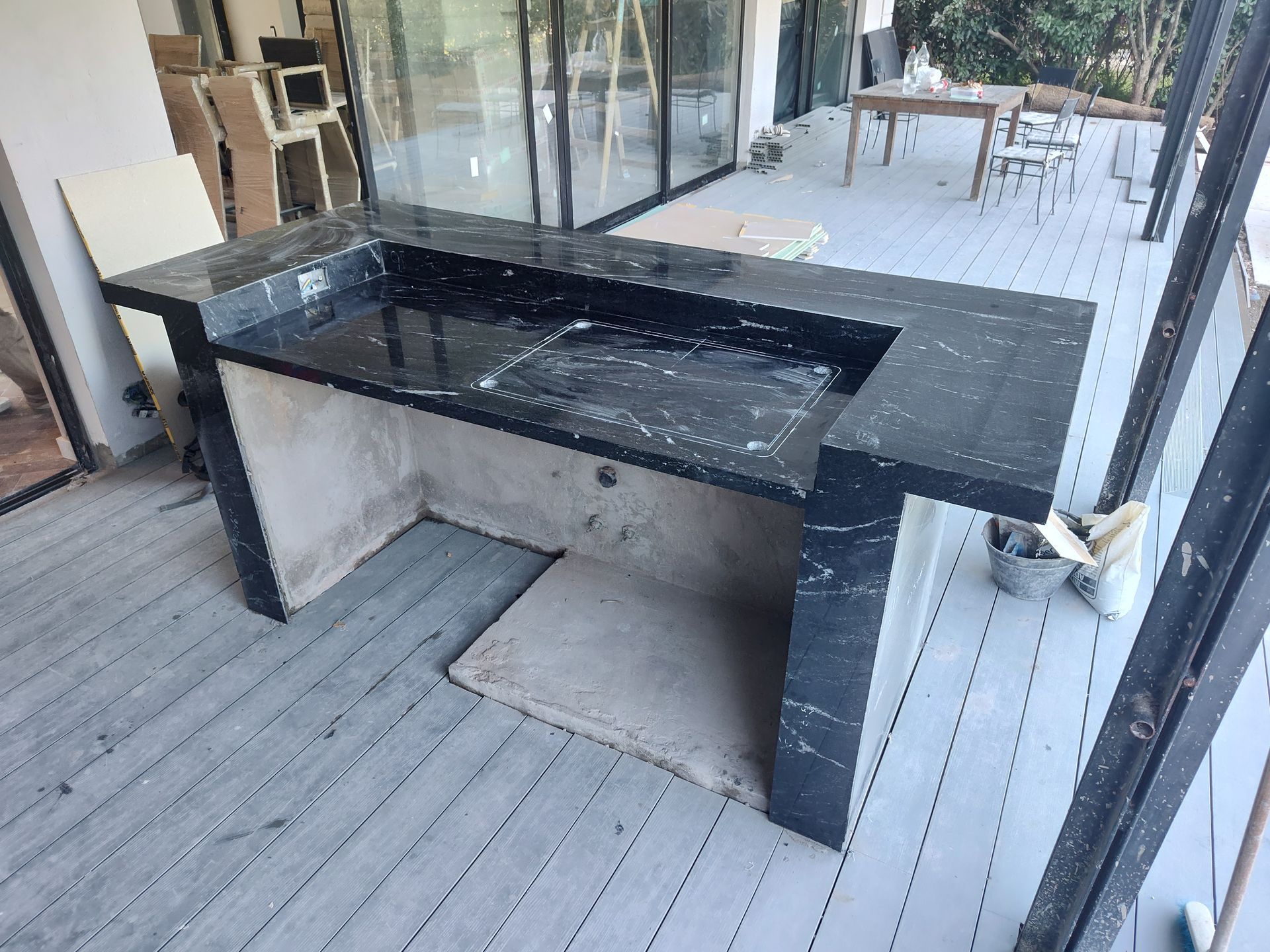 Encimera de granito negro para exterior con fregadero incorporado en una terraza.
