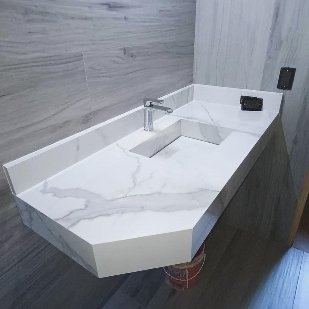 Encimera de mármol blanco con lavabo integrado en baño.