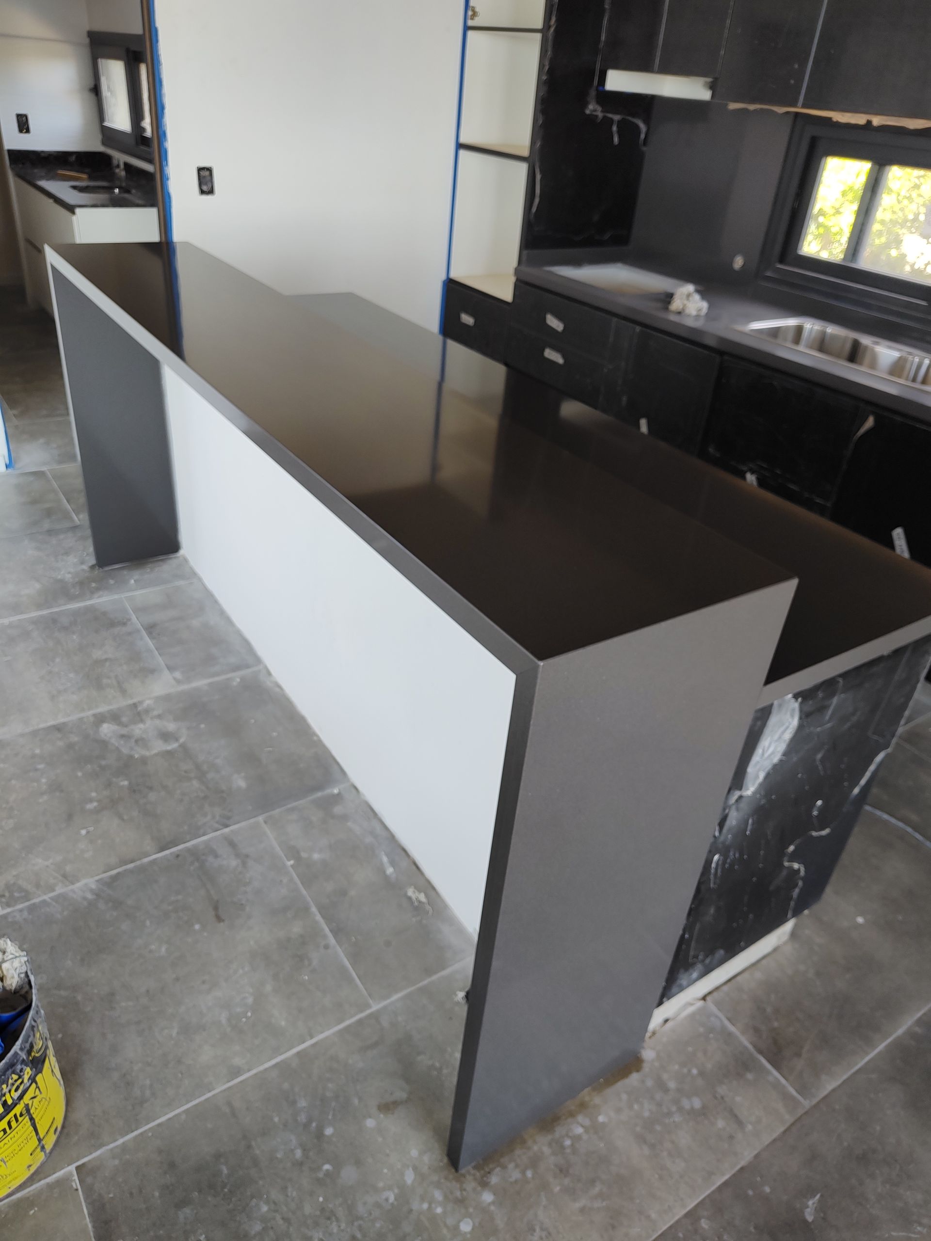 Isla de cocina moderna con encimera oscura, laterales blancos y grises. Suelo de baldosas grises.