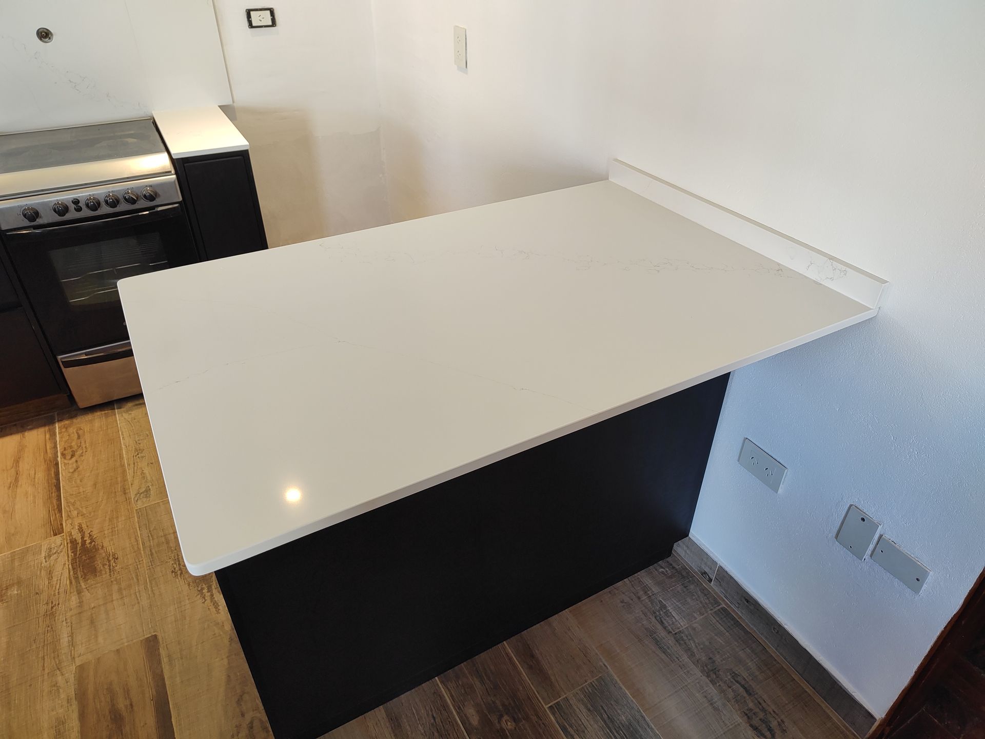Encimera de cocina con encimera blanca y base de armario negra. Incluye estufa de gas.