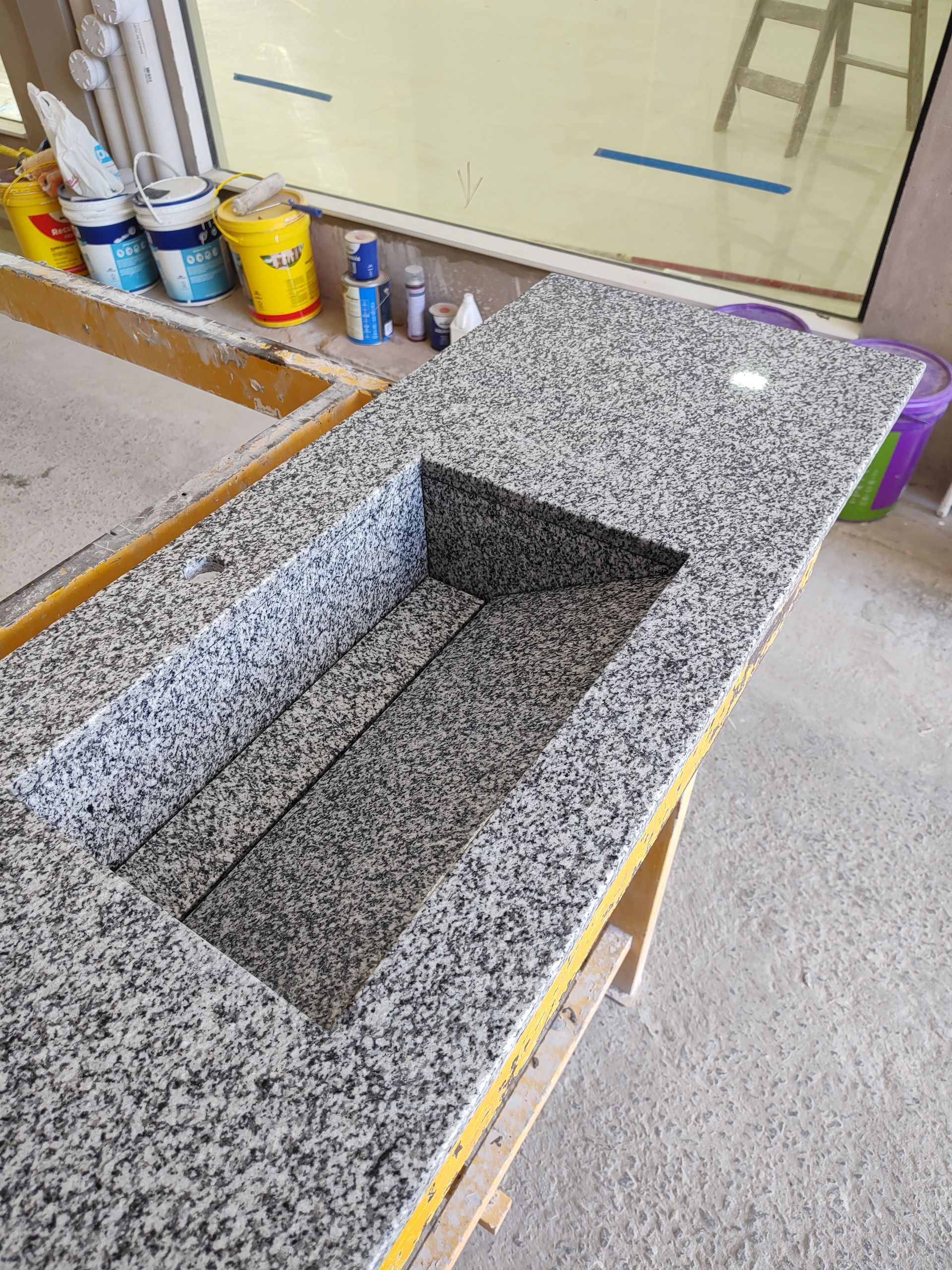 Encimera de granito con hueco para fregadero, en construcción. Piedra moteada gris y blanca sobre un marco de madera