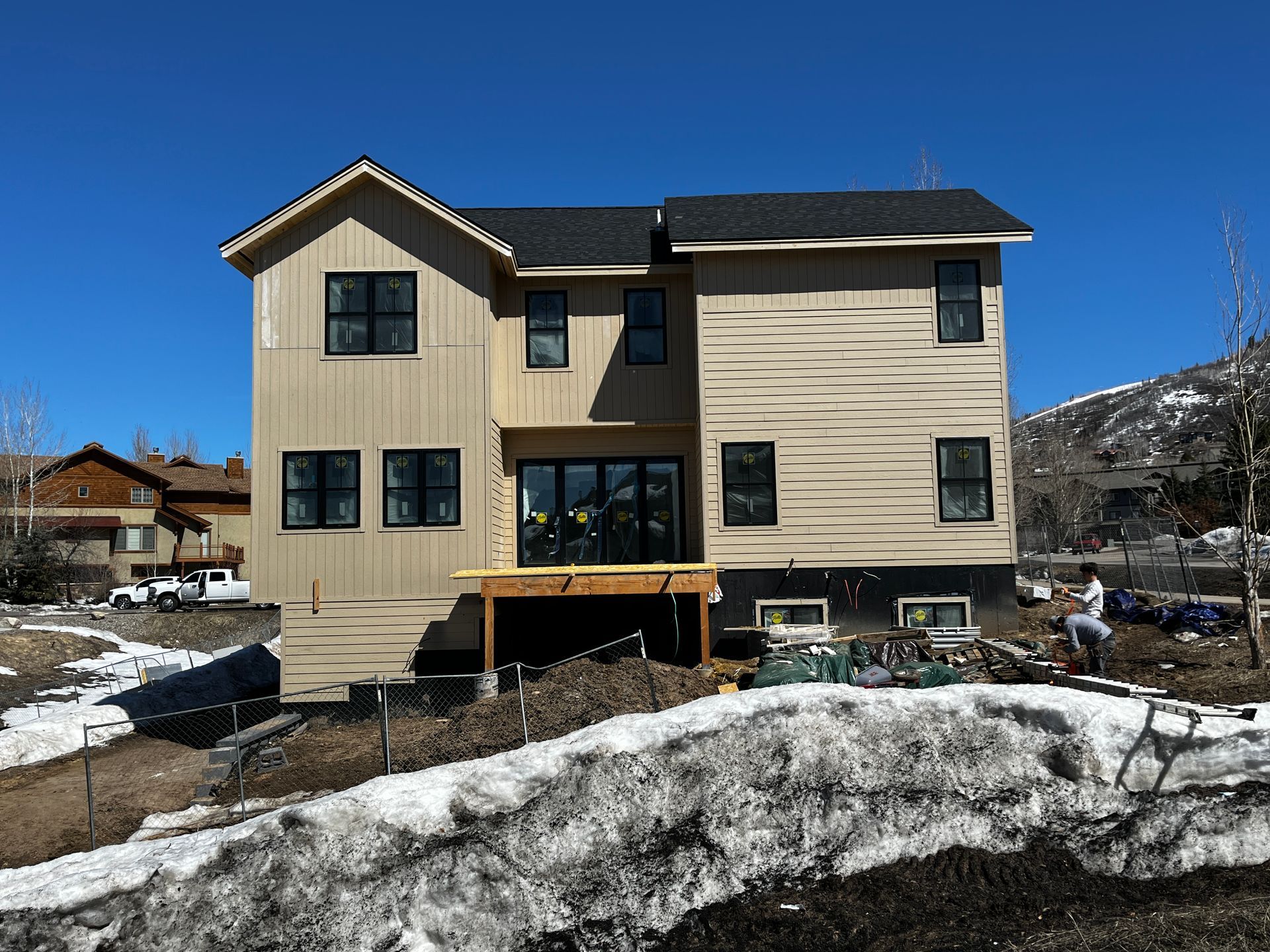 A large house with a lot of windows is sitting on top of a snow covered hill.