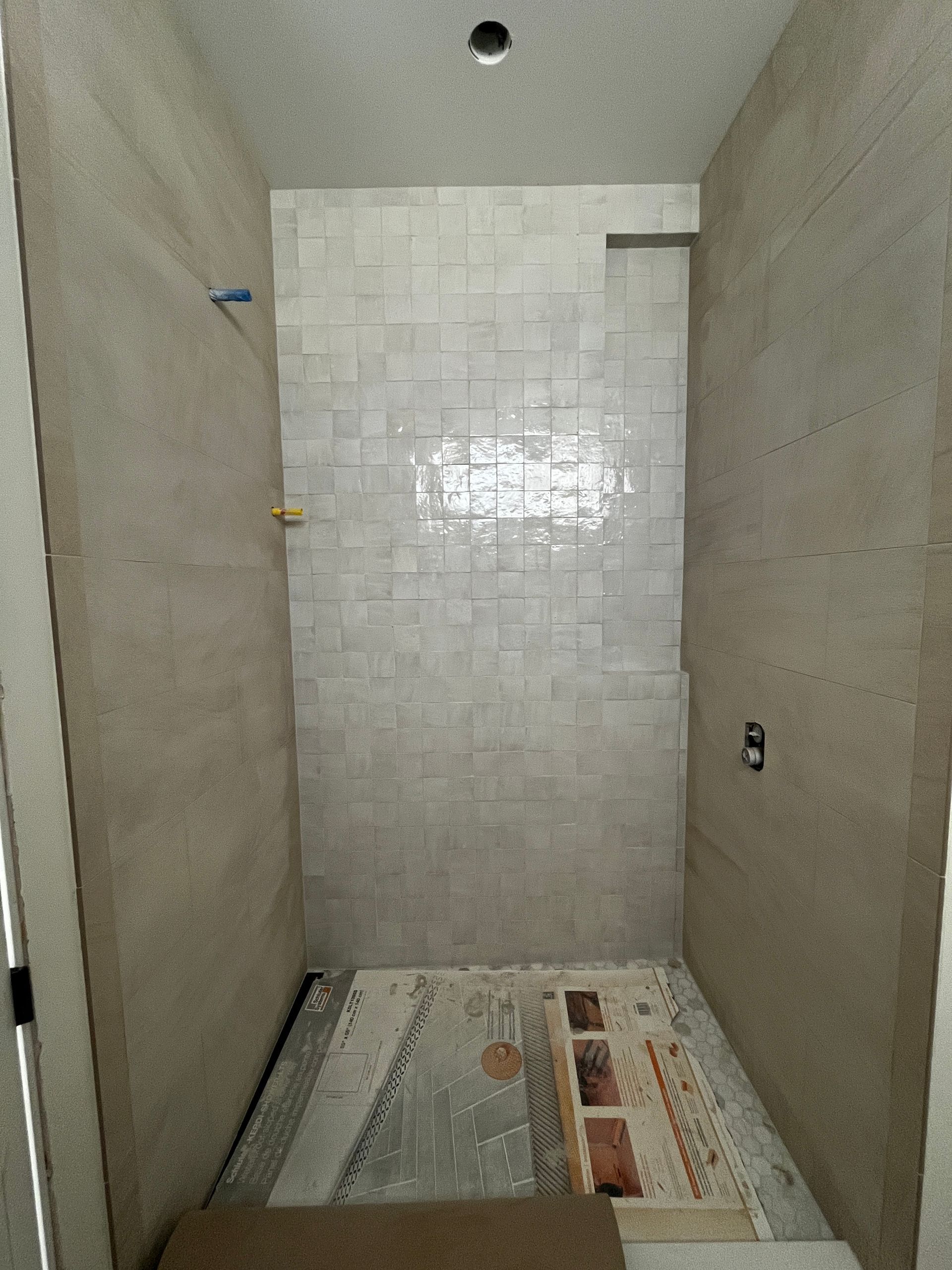 An empty living room with tile floors and a kitchen in the background.