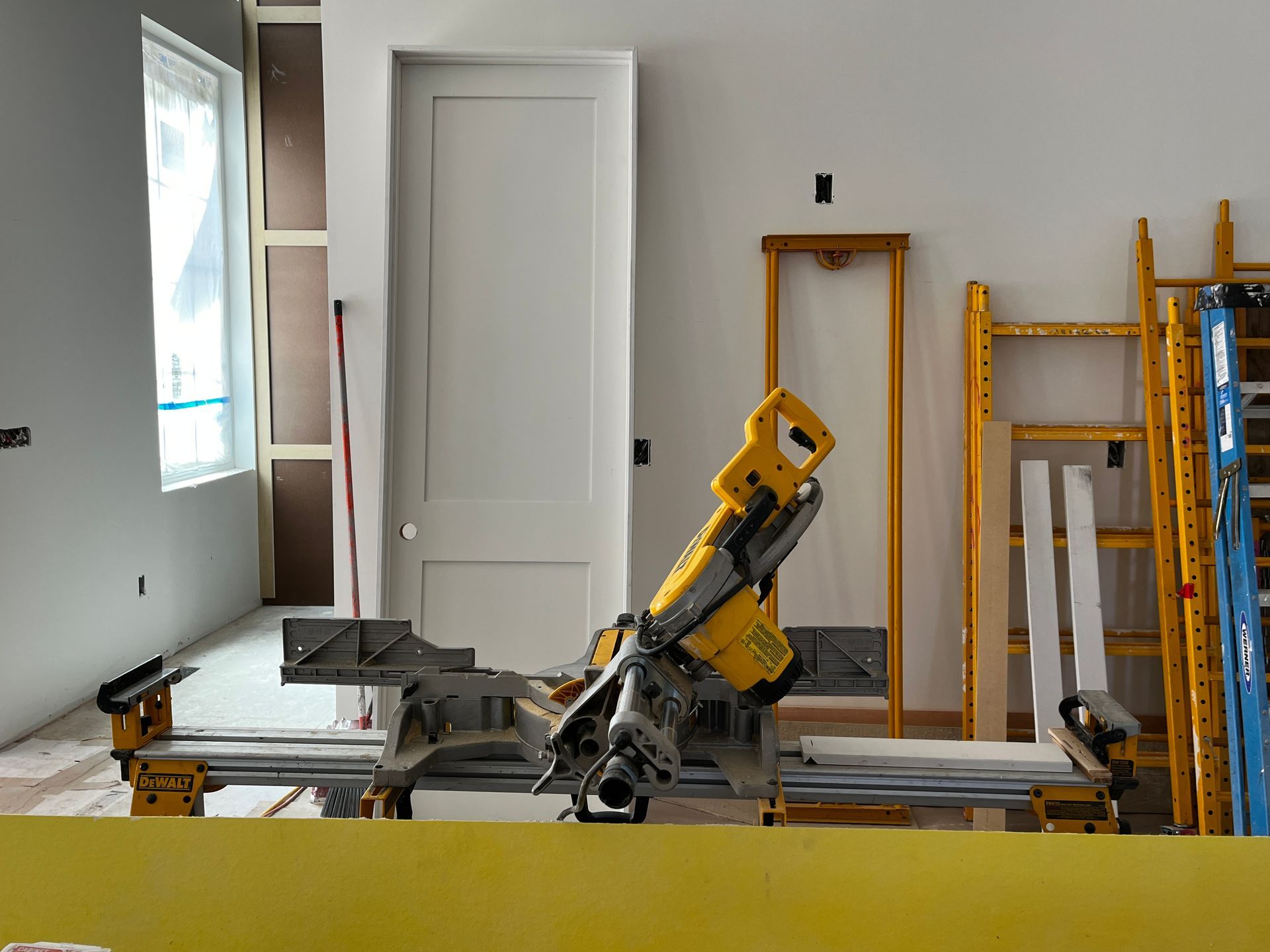 A yellow circular saw is sitting in a room under construction.