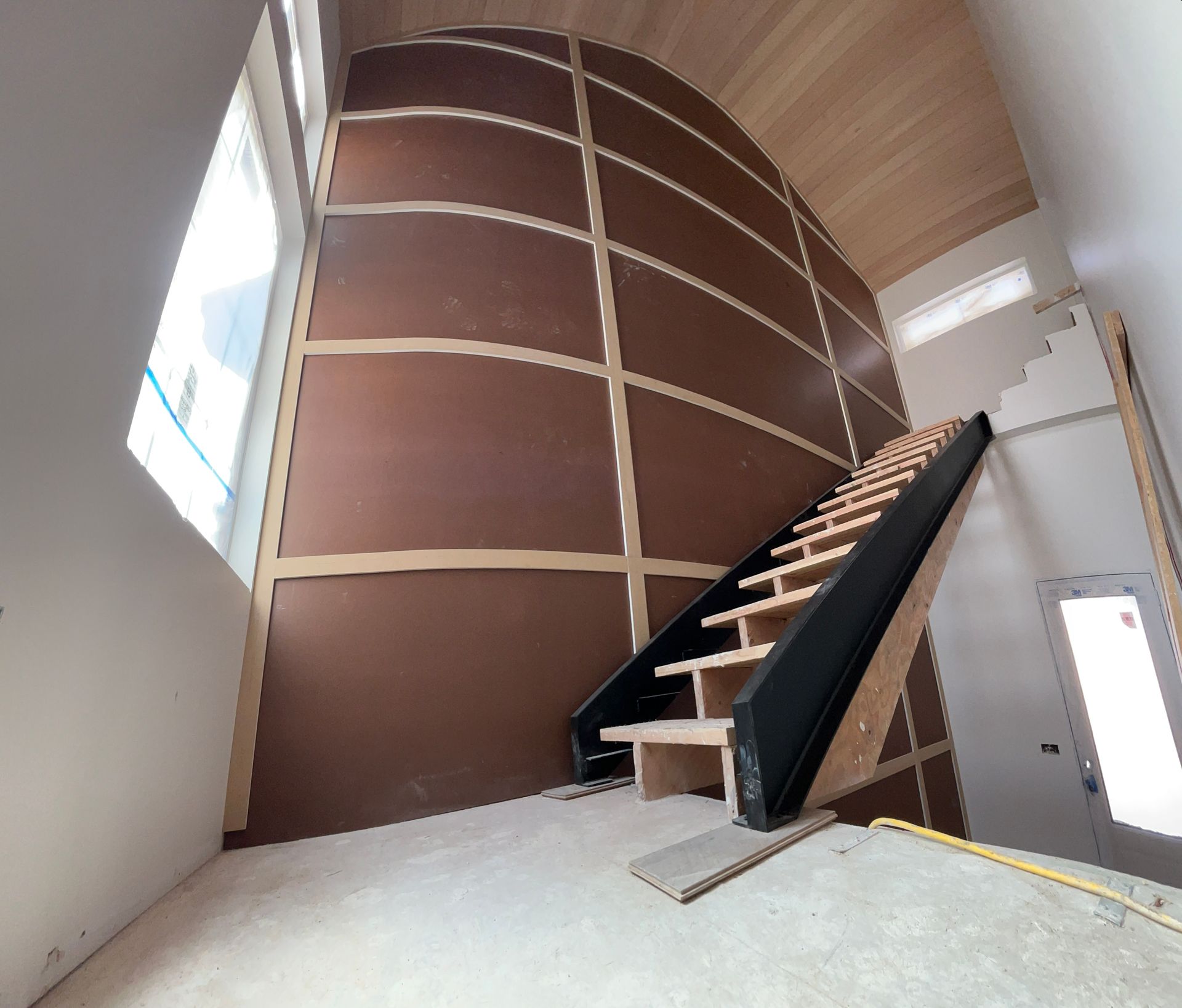 A wooden staircase with a curved wall behind it