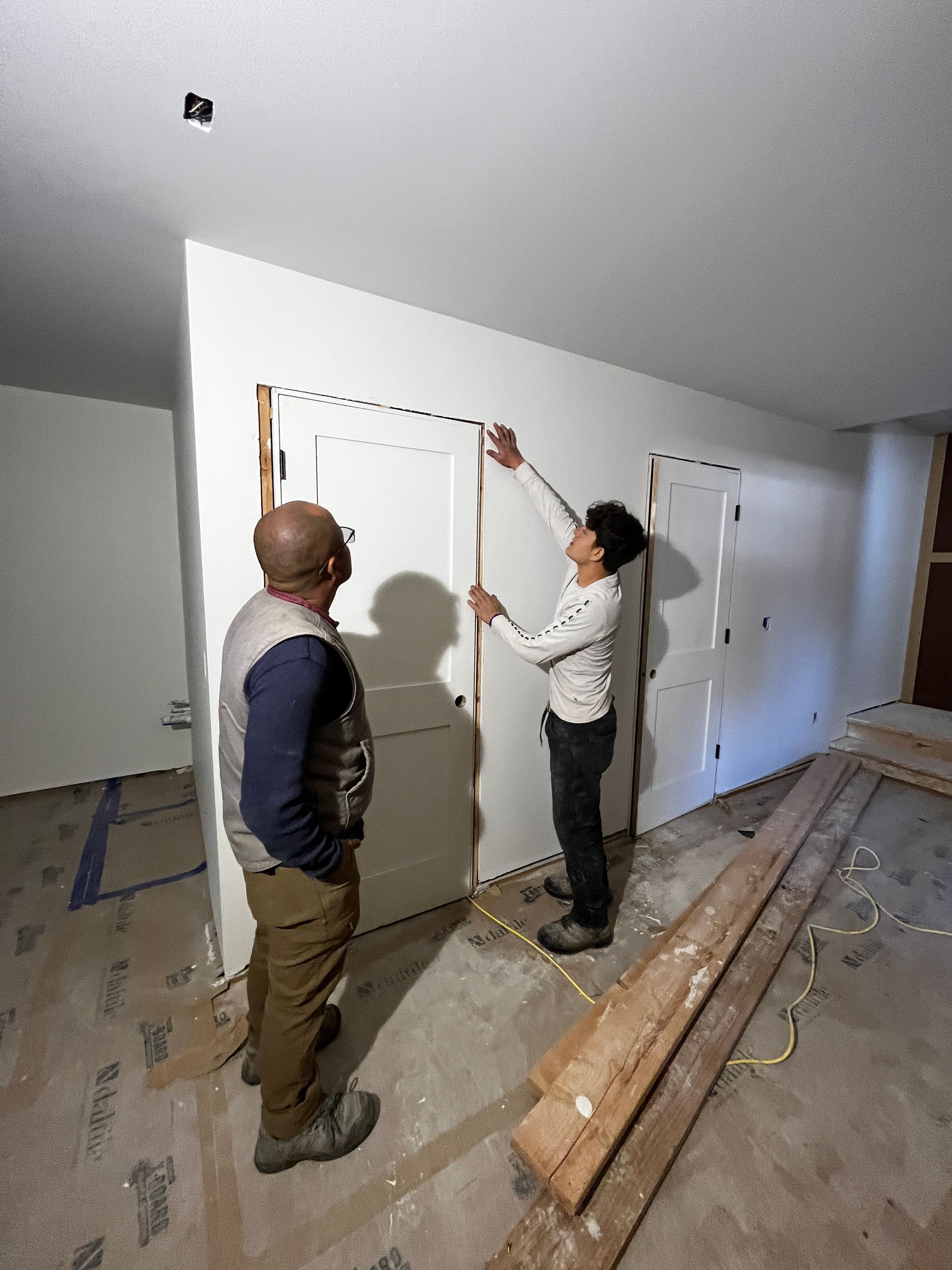 Two men are measuring a door with a tape measure.