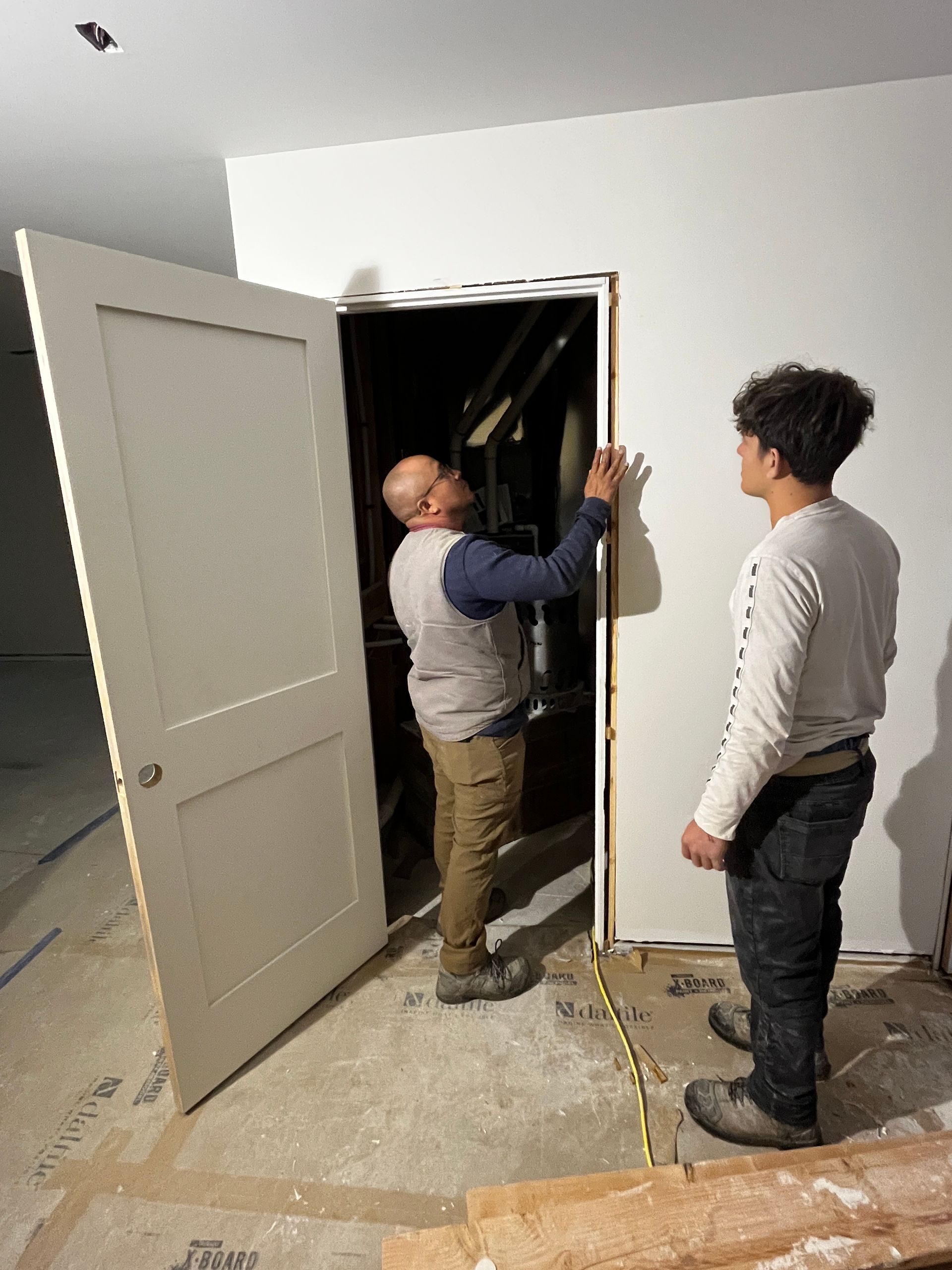 Two men are measuring a door in a room
