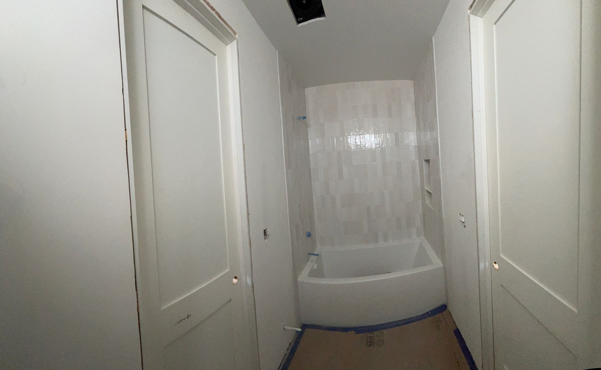 A bathroom with a tub , shower , and two doors.
