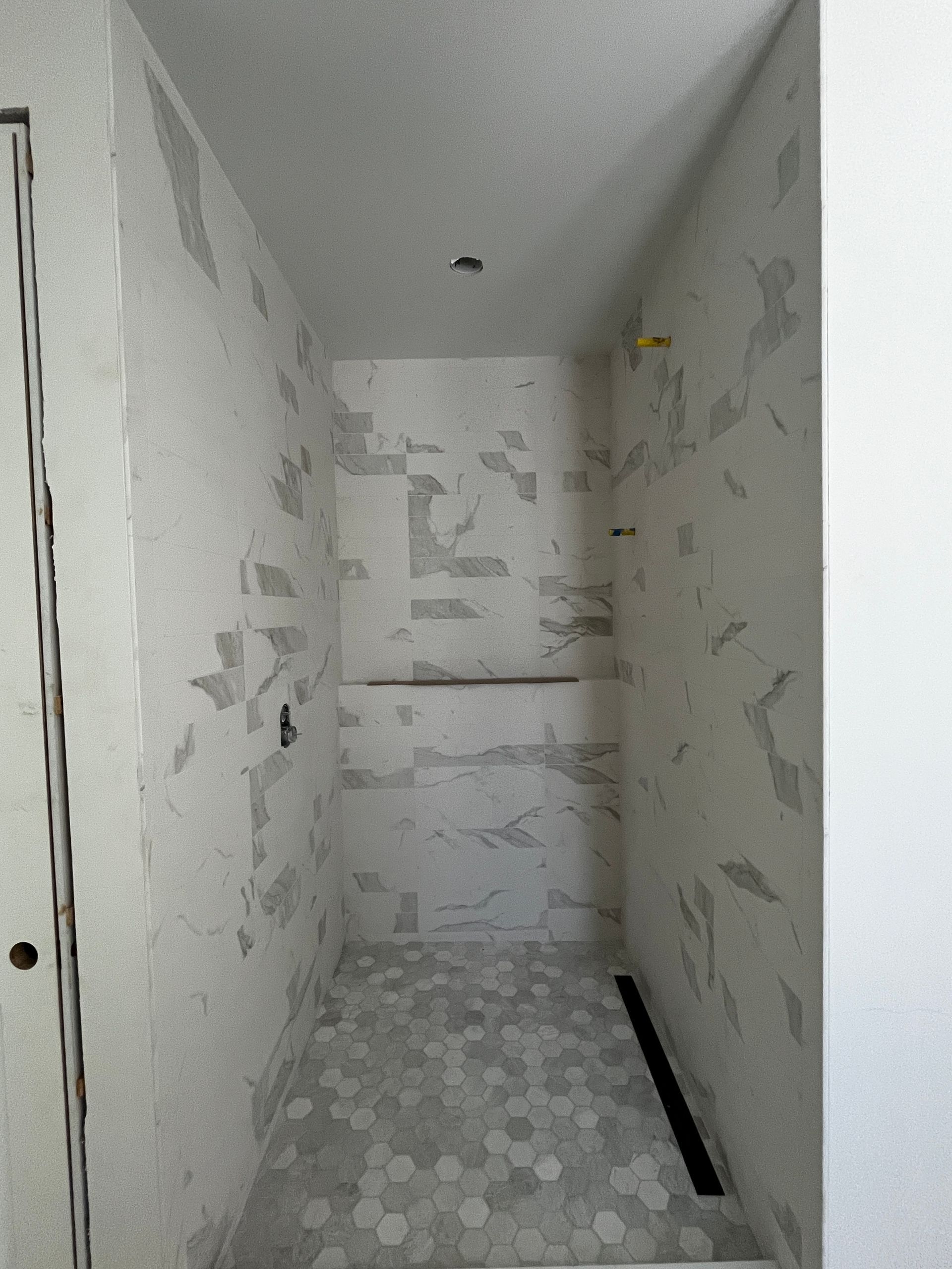 A bathroom with white tiles and a walk in shower.