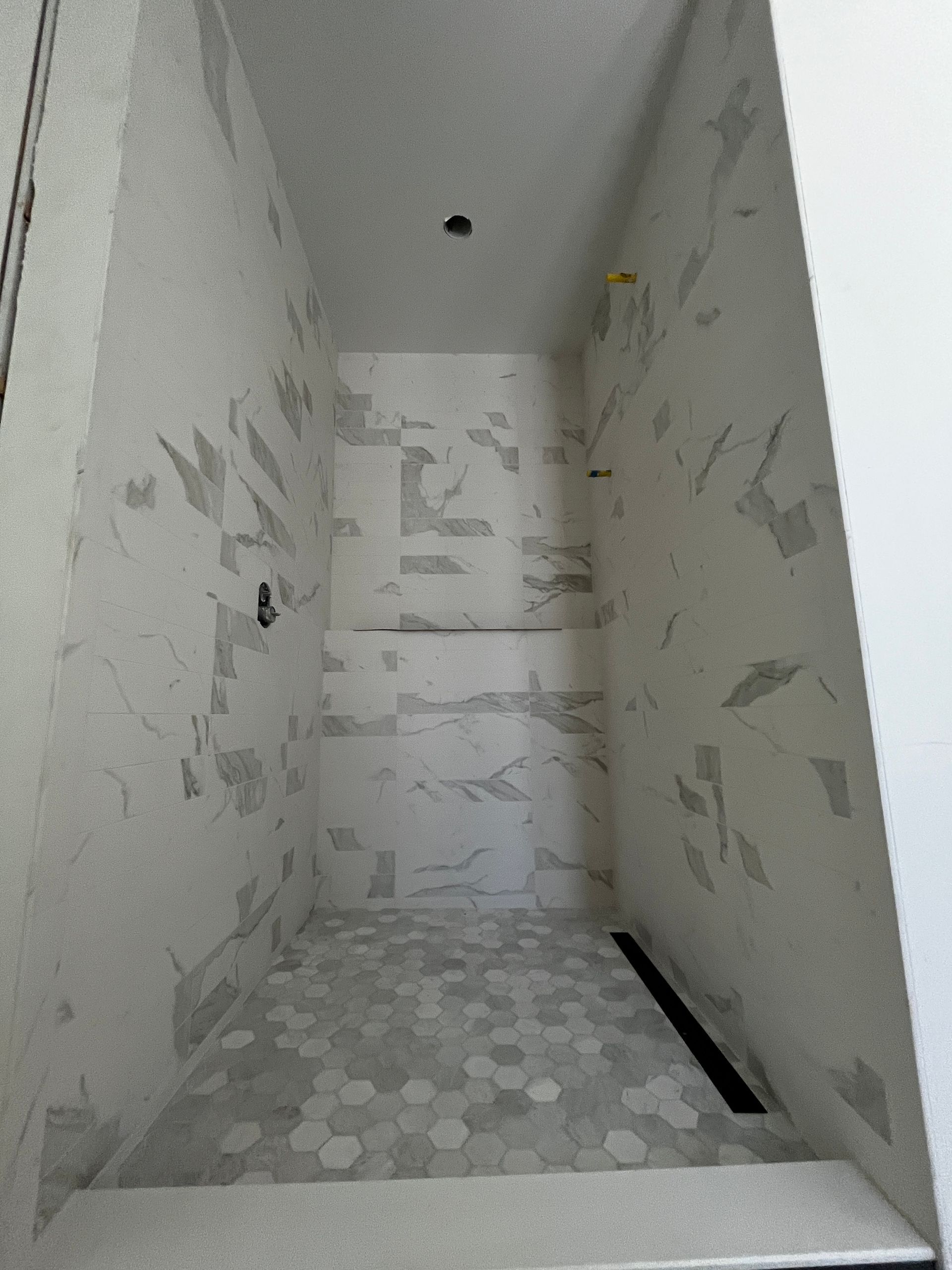 A walk in shower with marble tiles on the walls and floor.