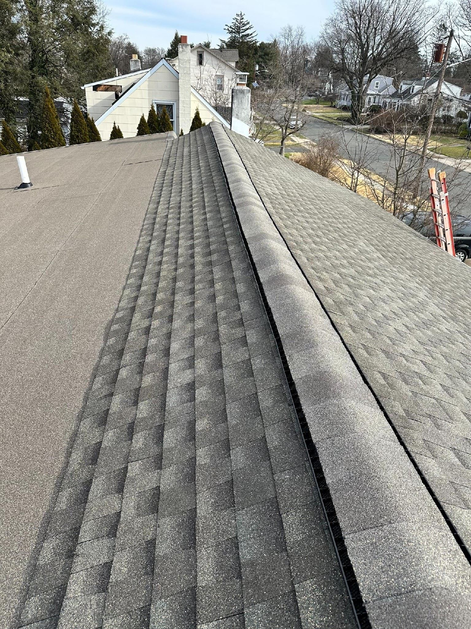 A roof with dark gray shingles and a raised ridge, seen from above.