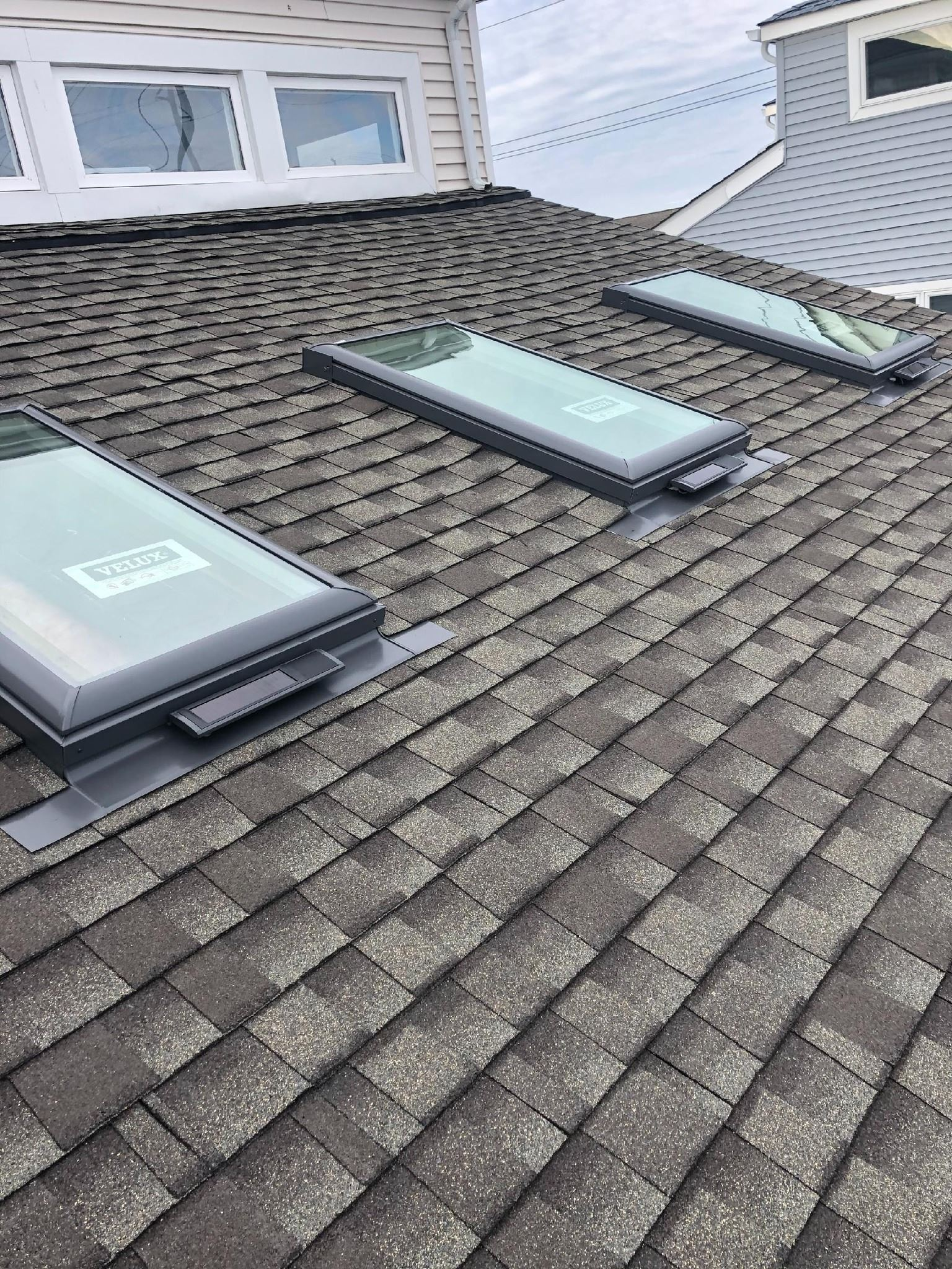 Three rectangular skylights on an asphalt shingle roof. The roof is angled.