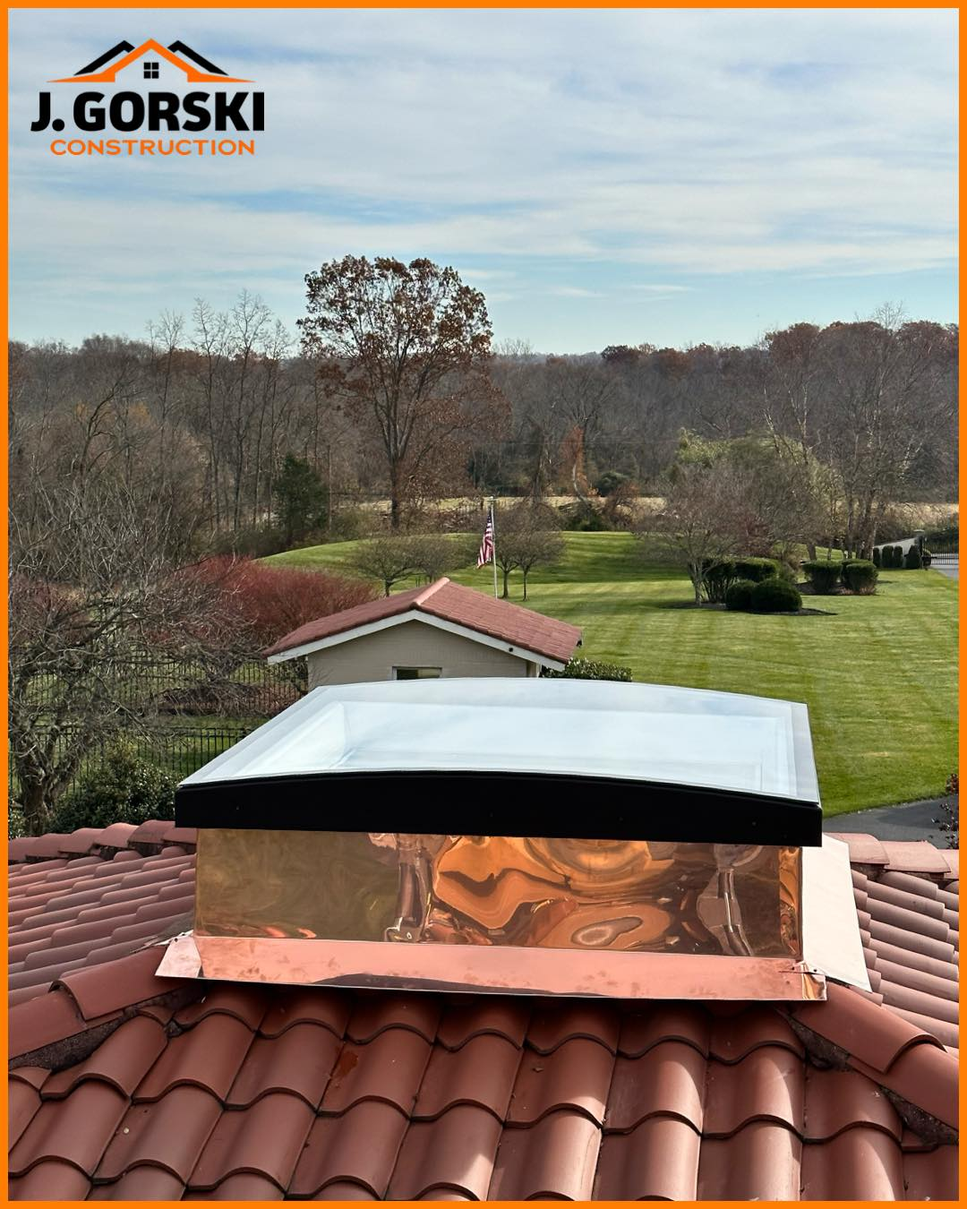 Copper-topped chimney on red tile roof, with trees and a house in the background.