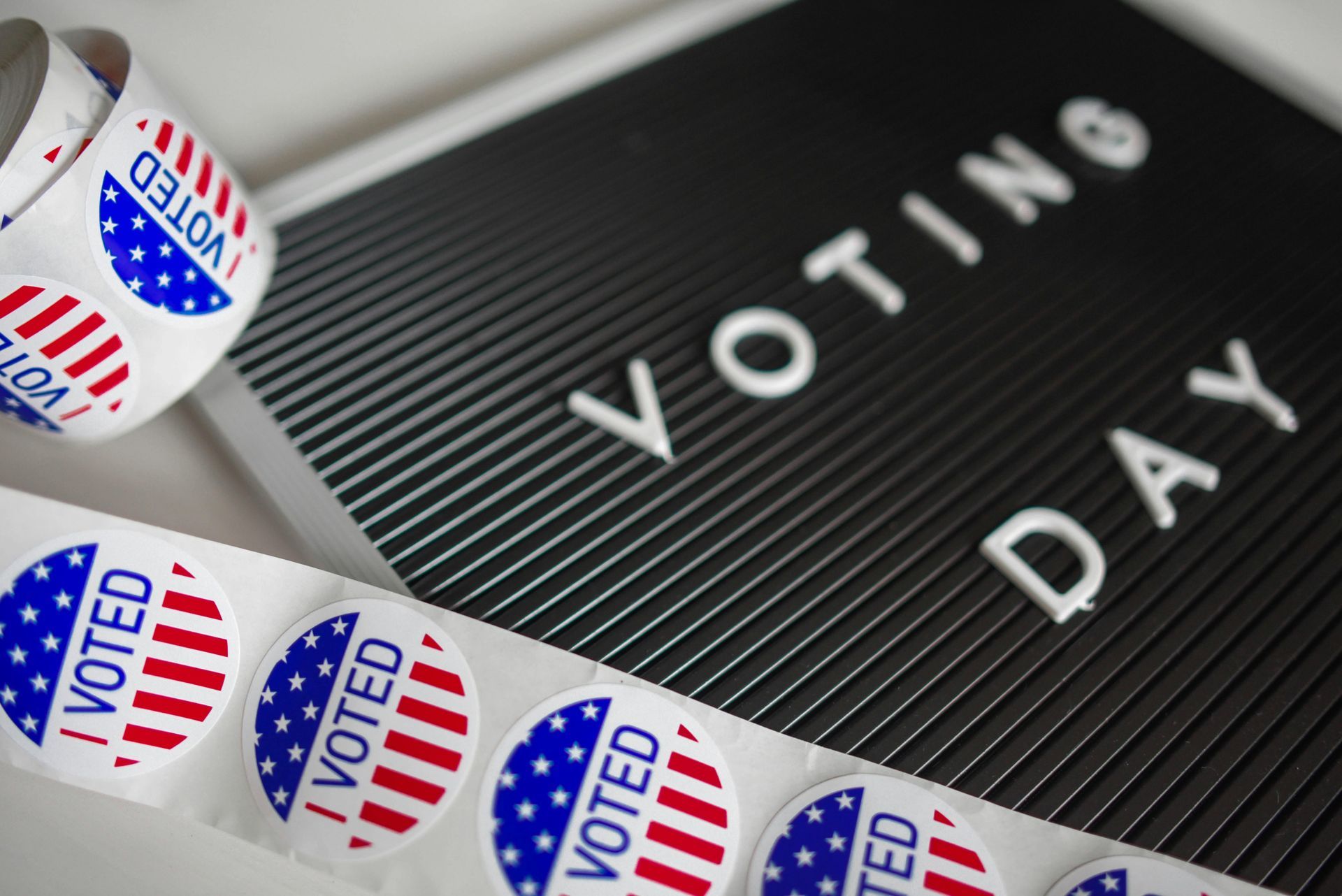 A roll of stickers that say `` i voted '' are sitting on top of a sign that says `` voting day ''.