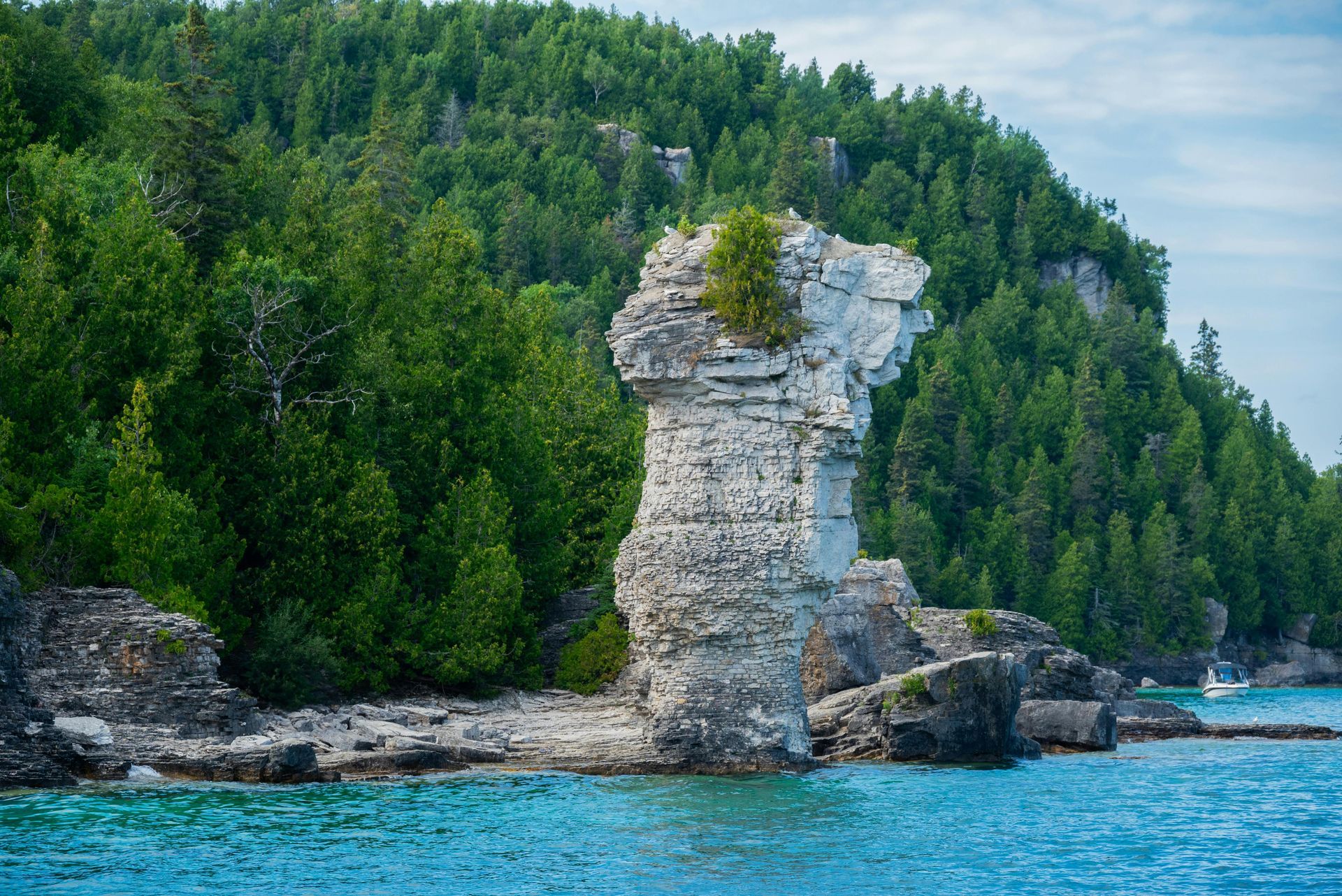 A large rock formation in the middle of a body of water surrounded by trees.