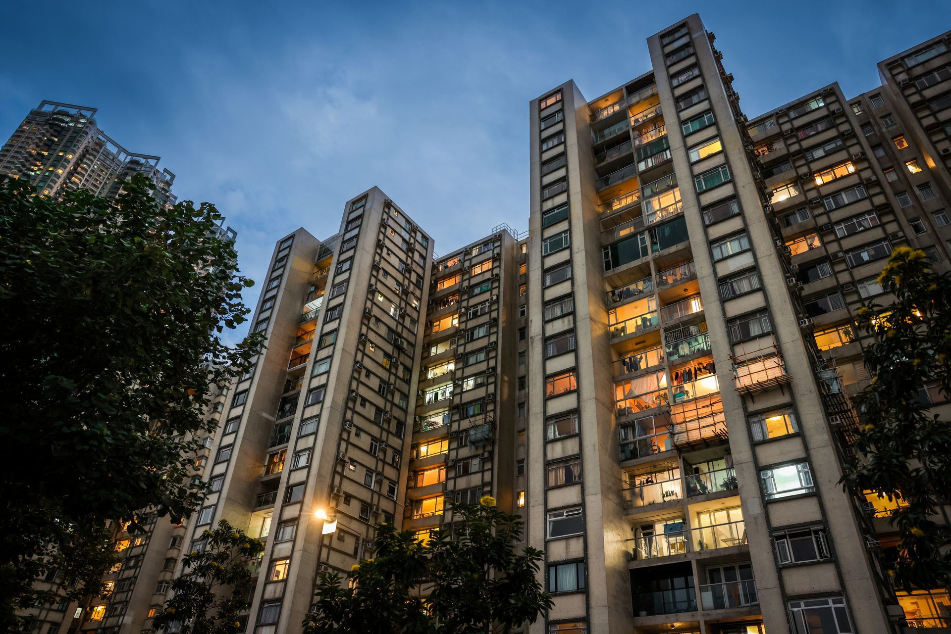 Tall concrete apartment buildings with lit windows against a dusk sky.