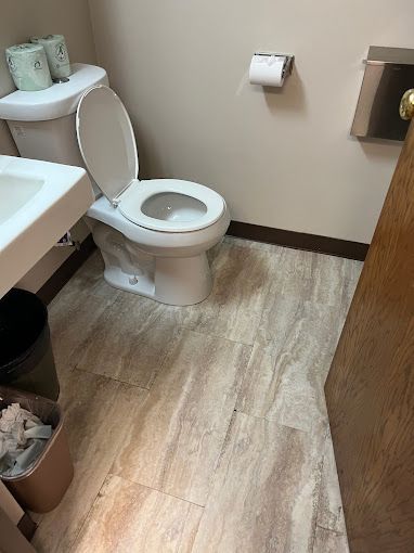 A bathroom with a toilet , sink and trash can.