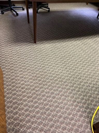 A carpeted floor with a table and chairs in a room.