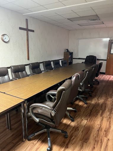 A conference room with a long table and chairs and a cross on the wall.
