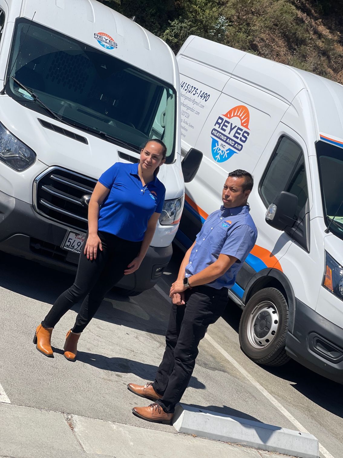 A man and a woman are standing in front of a row of vans — Novato, CA — Reyes Heating and Air Inc.
