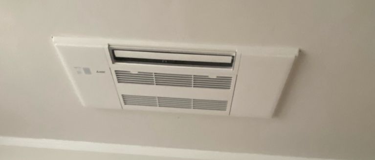 A white air conditioner is hanging from the ceiling of a room.