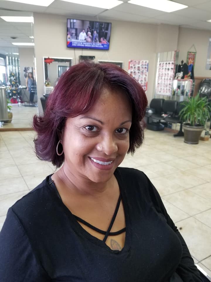 a woman with red hair smiling after her hair stylist appointment