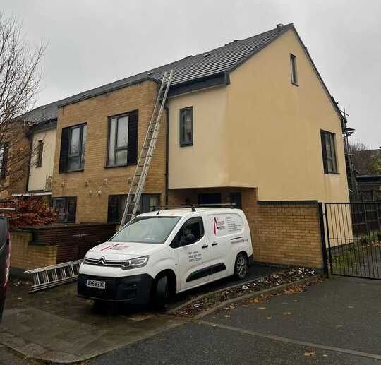 A white van is parked in front of a house under construction.