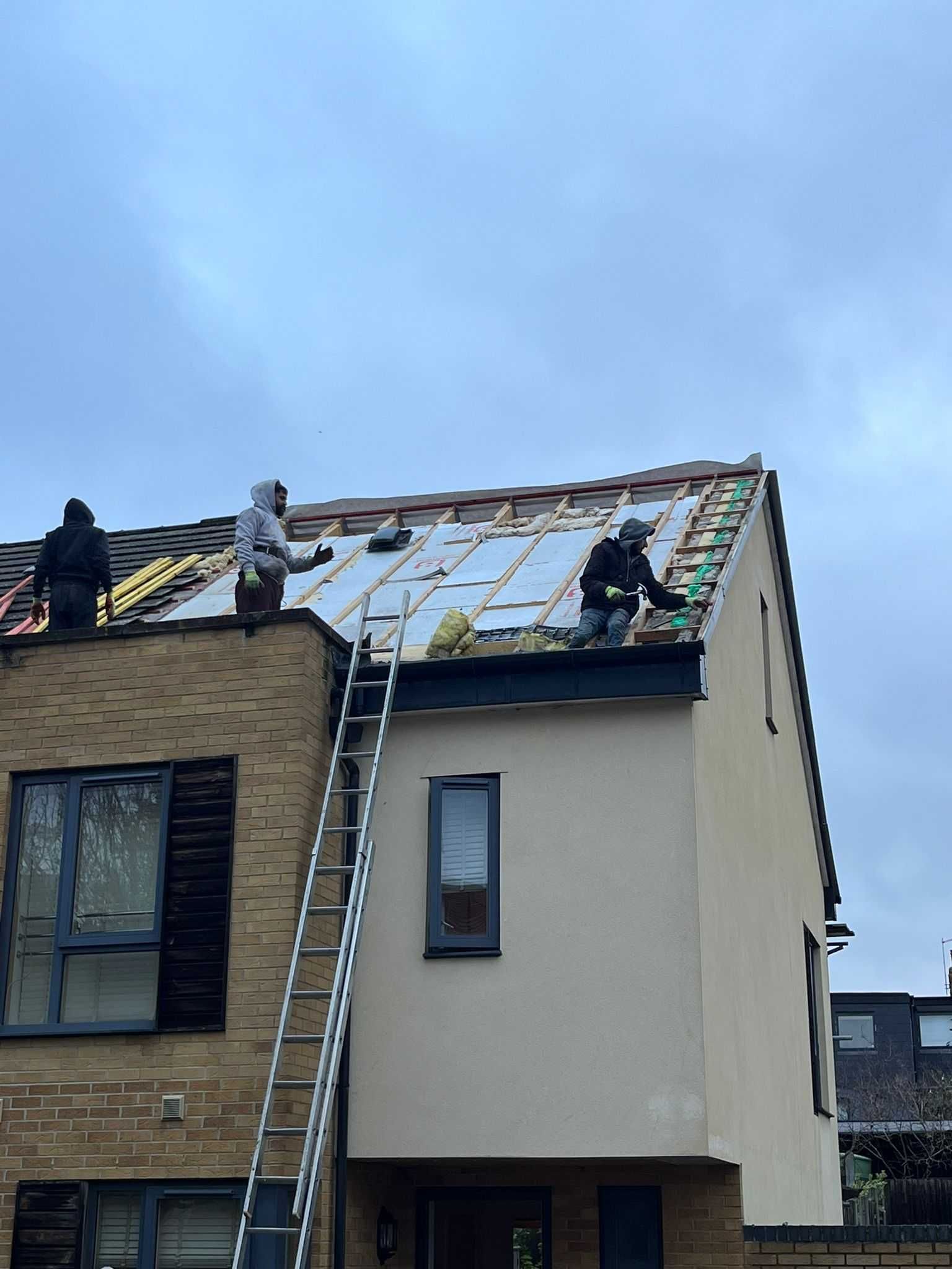 Two men are working on the roof of a house.