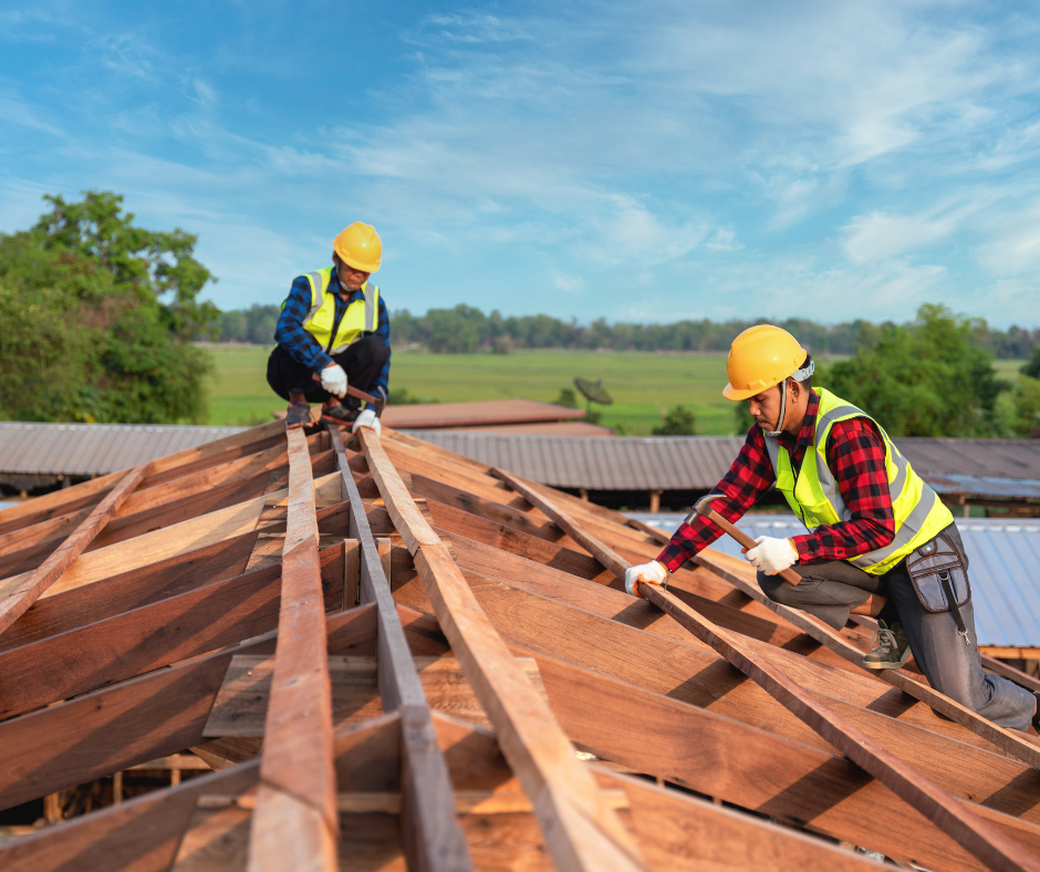 Two construction workers are working on a wooden roof.