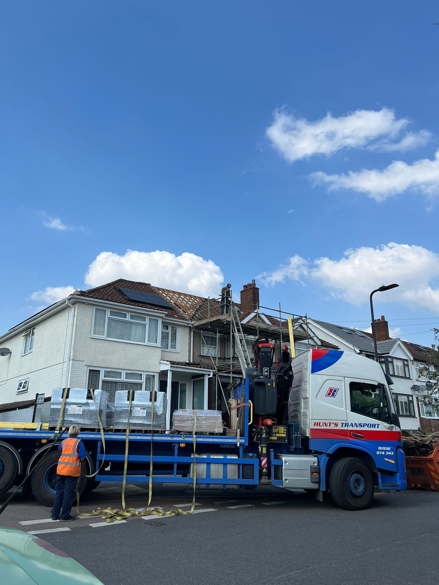 A blue and white truck is parked in front of a house.