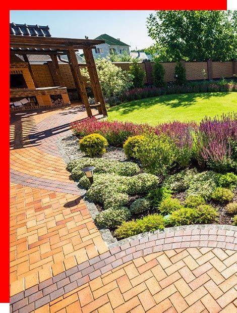 there is a brick walkway in the middle of the garden .